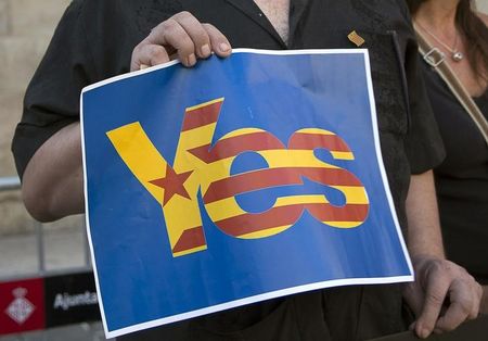 © Reuters. Catalunya's separatist supporters hold a sign supporting Scotland's independence as they wave Esteladas (Catalan separatist flags) at Sant Jaume square in Barcelona