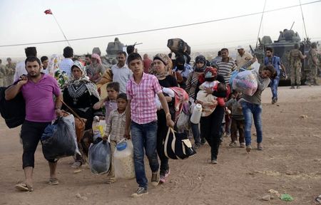 © Reuters. Syrian Kurds walk with their belongings after crossing into Turkey at the Turkish-Syrian border, near the southeastern town of Suruc in Sanliurfa province