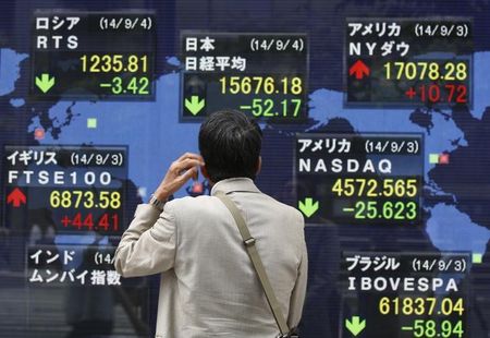 © Reuters. A man looks at an electronic board displaying Japan's Nikkei average and the stock price indexes of various countries outside a brokerage in Tokyo