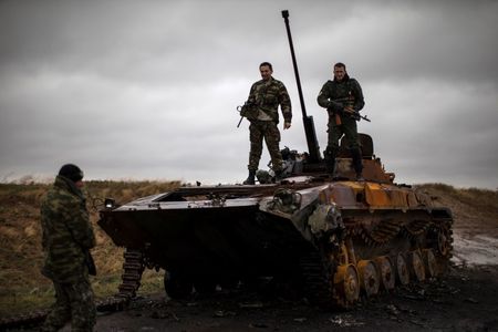 © Reuters. Pro-Russian rebels stand on top of a burnt-out Ukrainian armoured personnel carrier near the village of Novokaterinovka, eastern Ukraine