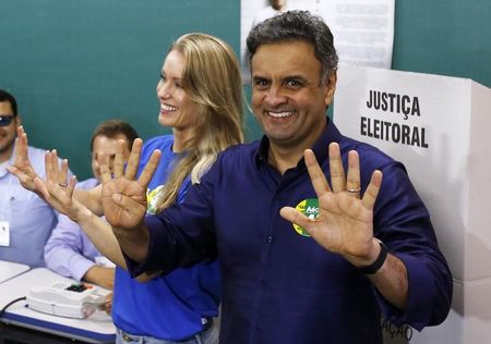 © Reuters. Aécio Neves (PSDB) e sua mulher, Letícia, posam para fotos em sala de votação em Belo Horizonte