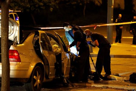 © Reuters. Israeli policemen inspect a car wreck in Jerusalem