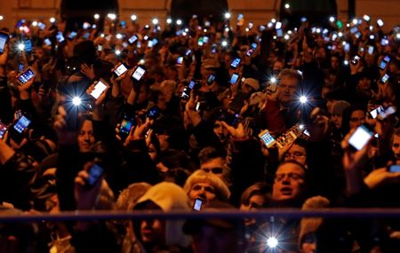 © Reuters. People hold up their mobile phones as they protest against a new tax on Internet data transfers in the centre of Budapest