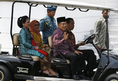 © Reuters. Widodo drives a golf car with Kalla, Iriana, and Mufidah, before posing for photographers with newly appointed cabinet ministers after an inauguration ceremony at the presidential palace in Jakarta