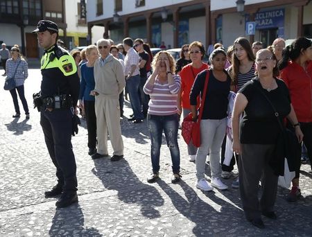 © Reuters. A police officer stands next to bystanders outside the Valdemoro town hall during a major anti-corruption raid