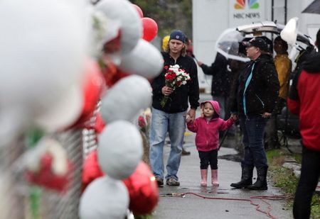 © Reuters. Chris Green and Angela Green, both graduates of Marysville-Pilchuck High School, walk with their daughter Dorothy as they take flowers to the makeshift memorial outside the school, in Marysville