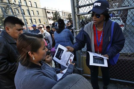 © Reuters. New York City Health department official hands out information on the Ebola virus outside a school near a Bronx New York apartment building, from where a 5-year-old boy who arrived from Guinea was taken to Bellevue Hospital in New York