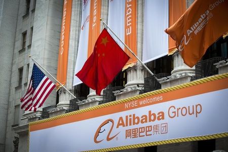 © Reuters. The Chinese and U.S. flags fly over signs of Alibaba Group Holding Ltd hung on the facade in front of the New York Stock Exchange before the company's initial public offering (IPO) under the ticker "BABA" in New York