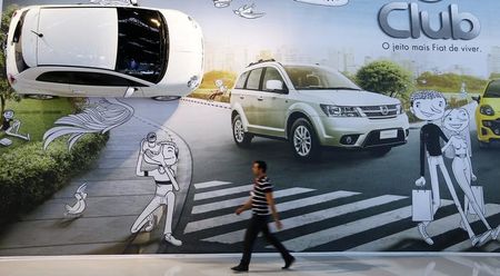 © Reuters. Um homem passa em frente a cartaz da Fiat no Salão Internacional de Automóveis em São Paulo 