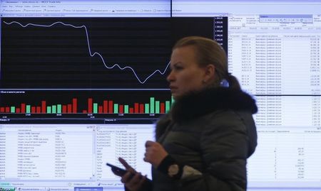 © Reuters. Женщина проходит мимо экрана с котировками на Московской бирже