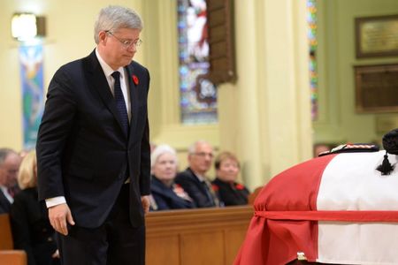 © Reuters. Canadian Prime Minister Stephen Harper walks by the coffin of Cpl. Nathan Cirillo as he makes his way to speak at his regimental funeral service in Hamilton, Ontario