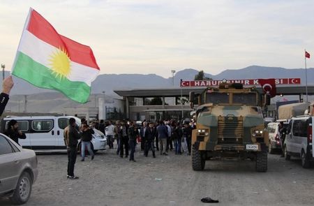 © Reuters. Um homem agita a bandeira curda conforme comboio atravessa a fronteira entre Turquia e Iraque 