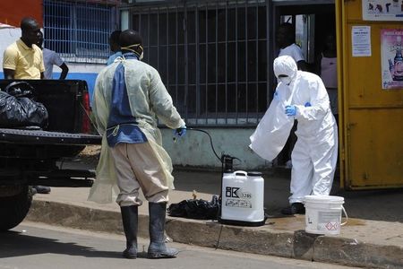 © Reuters. A member of a burial team prepares to spray a colleague with chlorine disinfectant in Monrovia