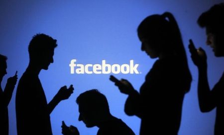 © Reuters. People pose with laptops in front of projection of Facebook logo in this picture illustration taken in Zenica