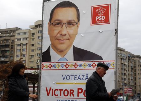 © Reuters. People walk past a banner depicting Victor Ponta, Romania's Prime Minister and leader of ruling leftist coalition in Bucharest