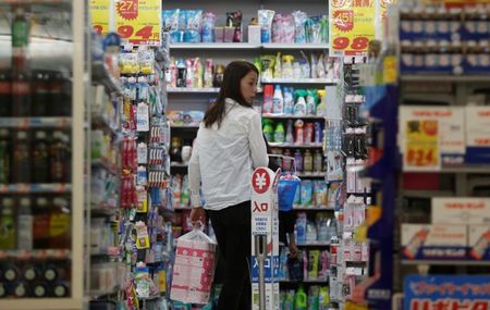 © Reuters. A shopper looks at items as she queues in line for the cashier at a discount store in Tokyo