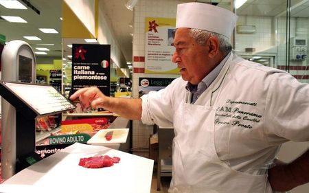 © Reuters. A butcher prices of a slice of meat at a supermarket in Milan