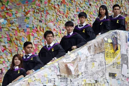 © Reuters. Graduated students of Hong Kong Polytechnic University have their pictures taken in front of a wall with messages of support for the pro-democracy movement in the part of Hong Kong's financial central district protesters are occupying