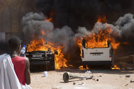 © Reuters. Homem observa carros em chamas em hotel da capital de Burkina Fasso, Ouagadougou