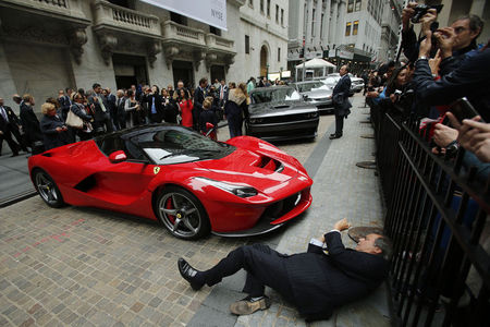 © Reuters. A man tries to take a picture of a Ferrari LaFerrari sports car parked at the entrance of the New York Stock Exchange in New York