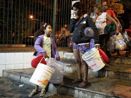 © Reuters. Residents line up to fill water buckets from a public tap at night as the eight-month rationing of water continues as a result of a record drought, in Itu