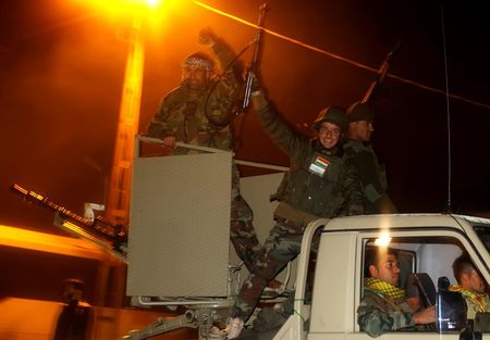 © Reuters. Kurdish peshmerga fighters celebrate atop an army vehicle as they move towards the Syrian town of Kobani from the border town of Suruc