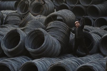 © Reuters. A labourer works on piles of steel coils in Taiyuan, Shanxi province