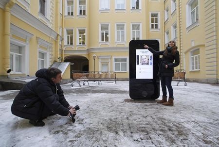 © Reuters. Homem tira foto de monumento em forma de iPhone para homenagear o fundador da Apple Steve Jobs em São Petersburgo