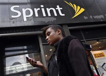 © Reuters. A woman uses her phone as she walks past a Sprint store in New York's financial district