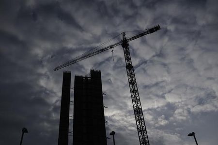 © Reuters. An industrial crane sits next to an apartment block under construction at Chelsea Wharf in London