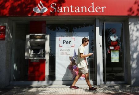 © Reuters. A man looks his mobile as he walks past a Santander bank office in El Masnou