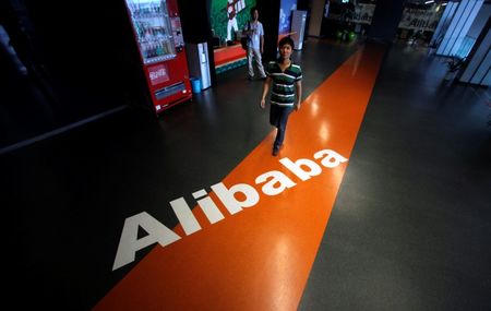 © Reuters. File photo of employee walking pass a logo of Alibaba during a media tour organised by government officials at its headquarters on the outskirts of Hangzhou