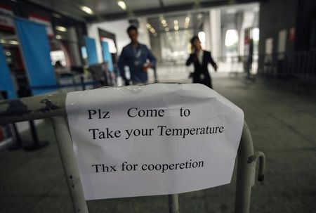 © Reuters. Sign requesting people to come have their temperature taken is seen at the entrance to the Canton Fair in Guangzhou