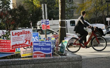 © Reuters. A cyclist peddles past a DC Cannabis Campaign sign in Washington