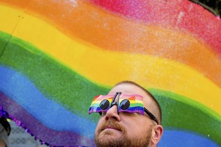 © Reuters. John Lucas stands in front of a rainbow flag at the San Francisco Gay Pride Festival in California