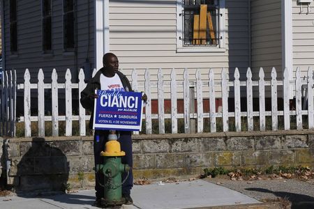 © Reuters. Man holds a campaign sign for independent mayoral candidate Cianci outside a campaign rally with United States first lady Obama and Democratic candidate for Rhode Island Governor Raimondo in Providence