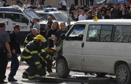 © Reuters. Bombeiros israelenses se preparam para rebocar veículo de um motorista palestino que avançou contra pedestres em Jerusalém 