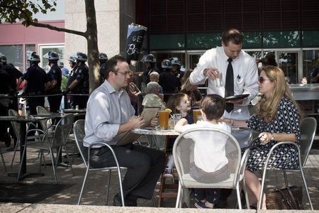 © Reuters. A family is served drinks at a restaurant while Occupy Wall Street activists protest through the streets of New York's Financial District on the one-year anniversary of the movement, in New York