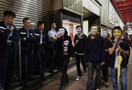 © Reuters. Manifestantes pró-democracia mascarados passam por rua ocupada por manifestantes em bairro de Hong Kong