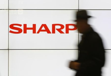 © Reuters. A pedestrian walks past a logo of Sharp Corp at a train station in Tokyo