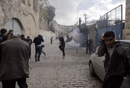 © Reuters. Palestinians react after Israeli police used a stun grenade to disperse a crowd in the Old City of Jerusalem