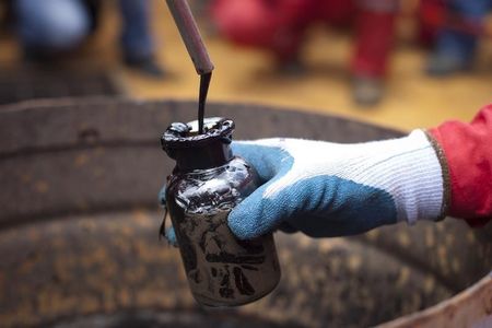 © Reuters. Рабочий берет образец сырой нефти со скважины венесуэльской компании PDVSA 