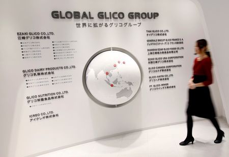 © Reuters. Employee of Ezaki Glico walks past a map displaying the companies in the Global Glico Group at Glicopia East, a museum of the company located next to its Kitamoto factory