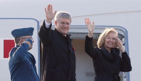 © Reuters. Canada's PM Harper and his wife Laureen wave while boarding a RCAF plane before departing for China, in Ottawa