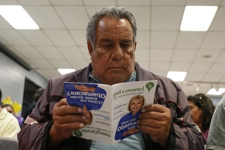 © Reuters. Dominguez, who does not have health insurance, reads a pamphlet at a health insurance enrollment event in Cudahy, California