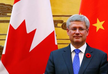 © Reuters. Canada's Prime Minister Harper stands in front of Chinese and Canadian national flags as he witnesses a signing ceremony at the Great Hall of the People in Beijing