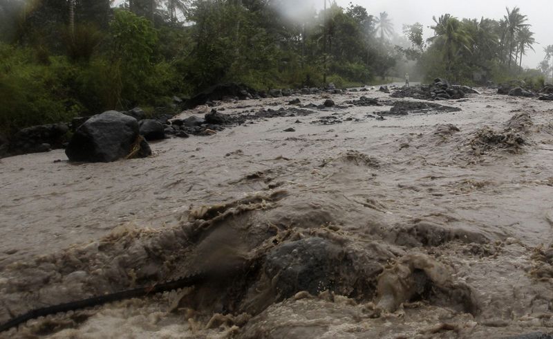 © Reuters. Volcanic rocks are washed onto a main road during a flash flood brought by Typhoon Hagupit in Guinobatan, Albay province southern Luzon