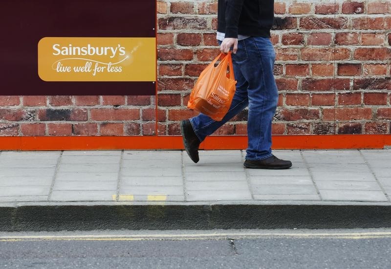 © Reuters. A shopper passes a signage for a Sainsbury's store in London