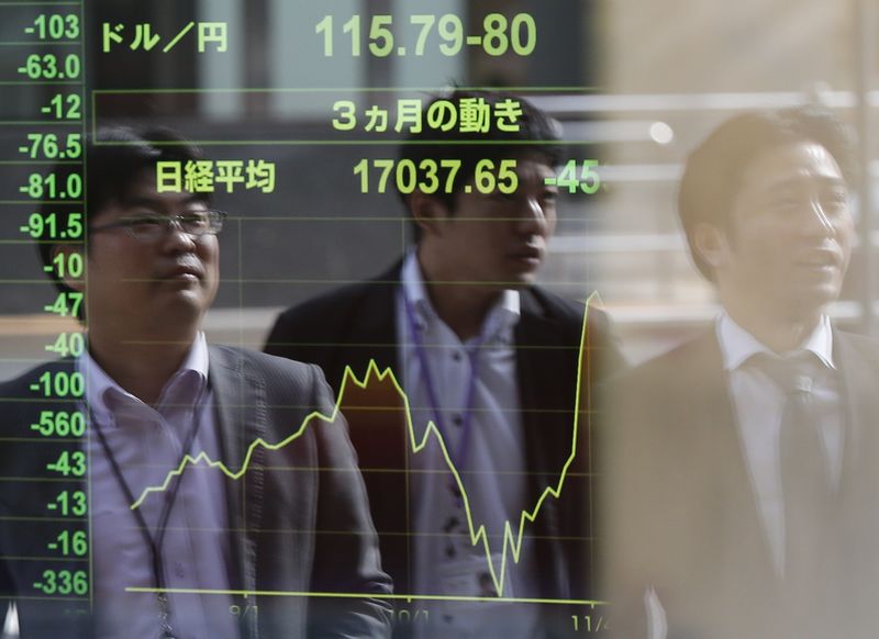 © Reuters. Passers-by are reflected on an electronic board at a brokerage in Tokyo