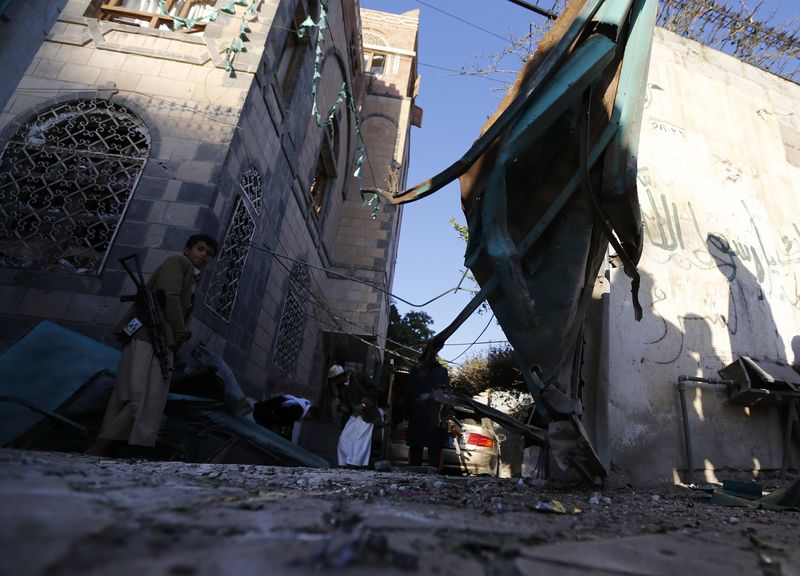 © Reuters. An armed man stands by a damaged gate at a house, belonging to a Shi'ite Houthi man, after a a bomb explosion in Sanaa